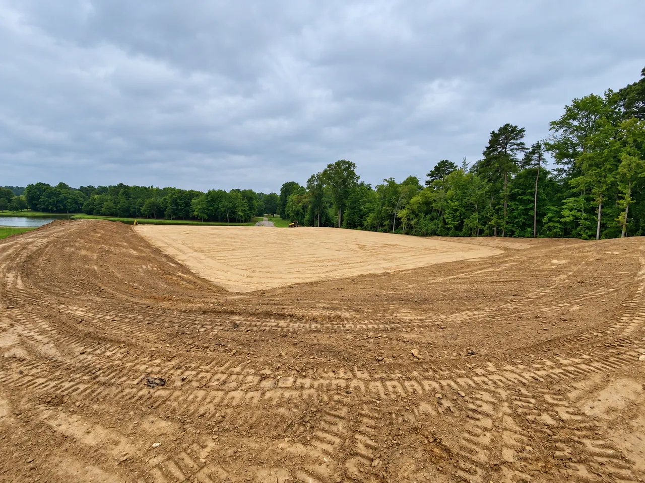 Freshly graded building pad and slopes on a wooded site